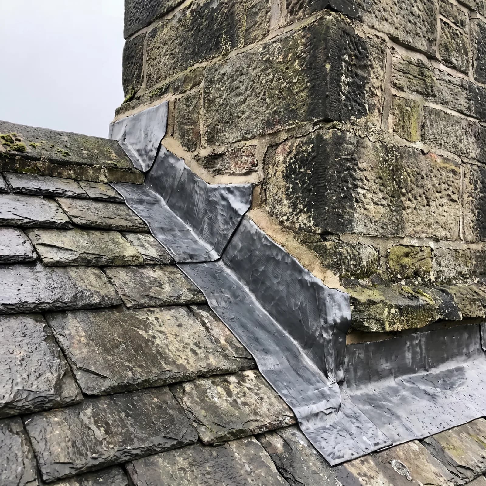 Hand-dressed lead flashing stepped into brickwork above a slate roof